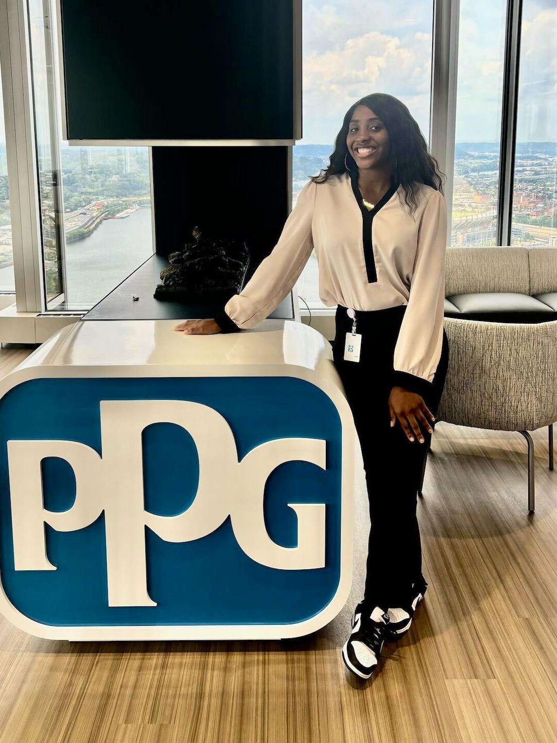 A student stands next to a PPG sign
