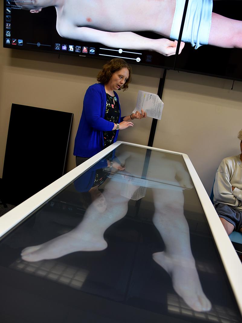 Cori Biddle, student engagement and outreach librarian, gives students a demonstration of the Anatomage Table.