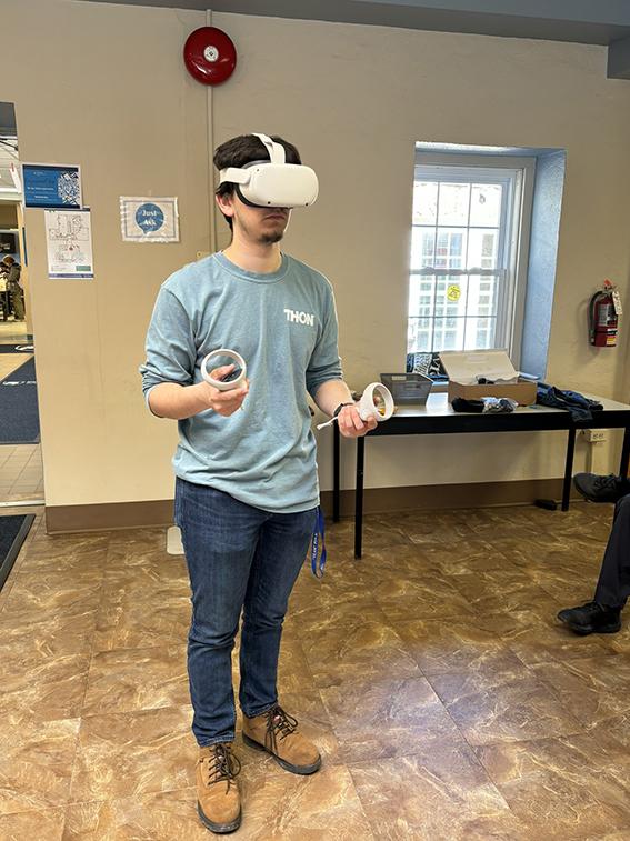A man standing and wearing a pair of virtual reality goggles, with controllers on each hand.