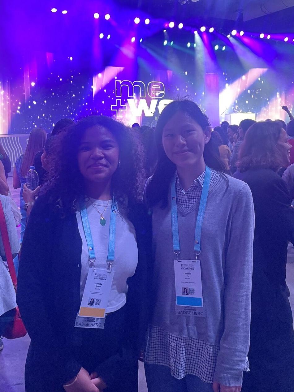 two college students at crowded event with purple lights in background