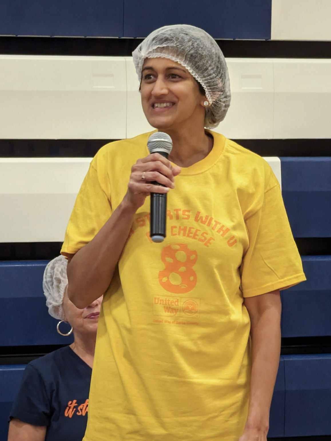 Pyati wearing hair net holding microphone speaking to crowd