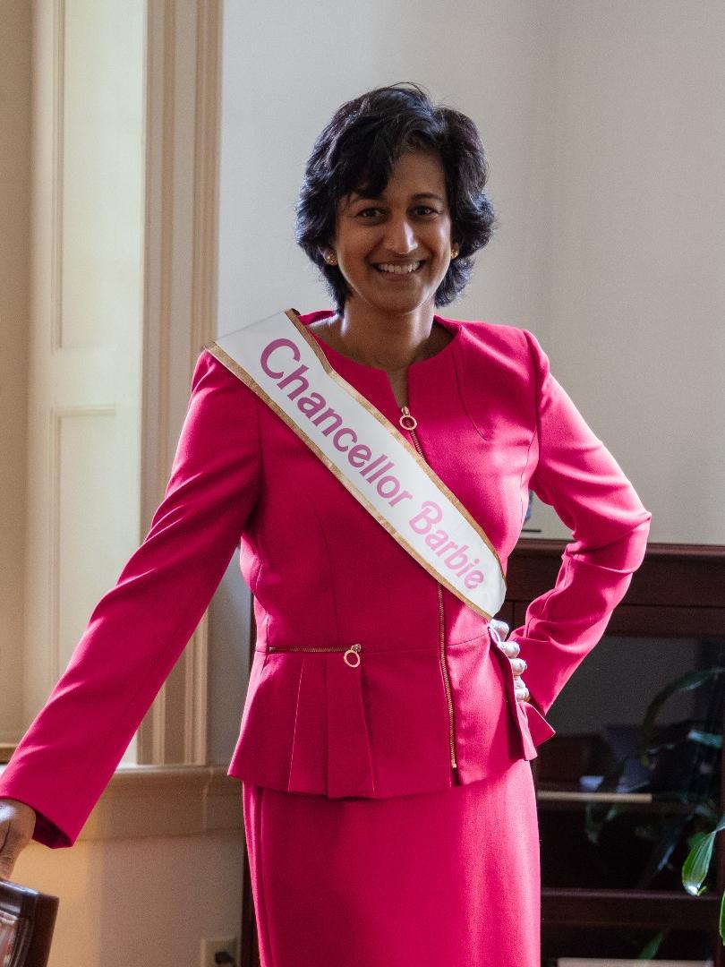 Radha Pyati wears a pink power suit with a ribbon reading "Chancellor Barbie"