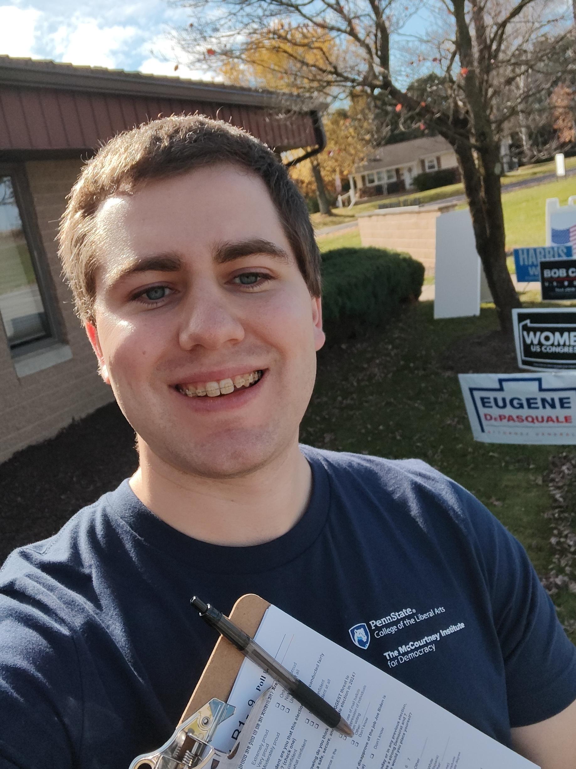 Justin Crofoot, assistant teaching professor of political science at Penn State, holds a clipboard with an exit poll survey in front of of a polling place on Election Day.
