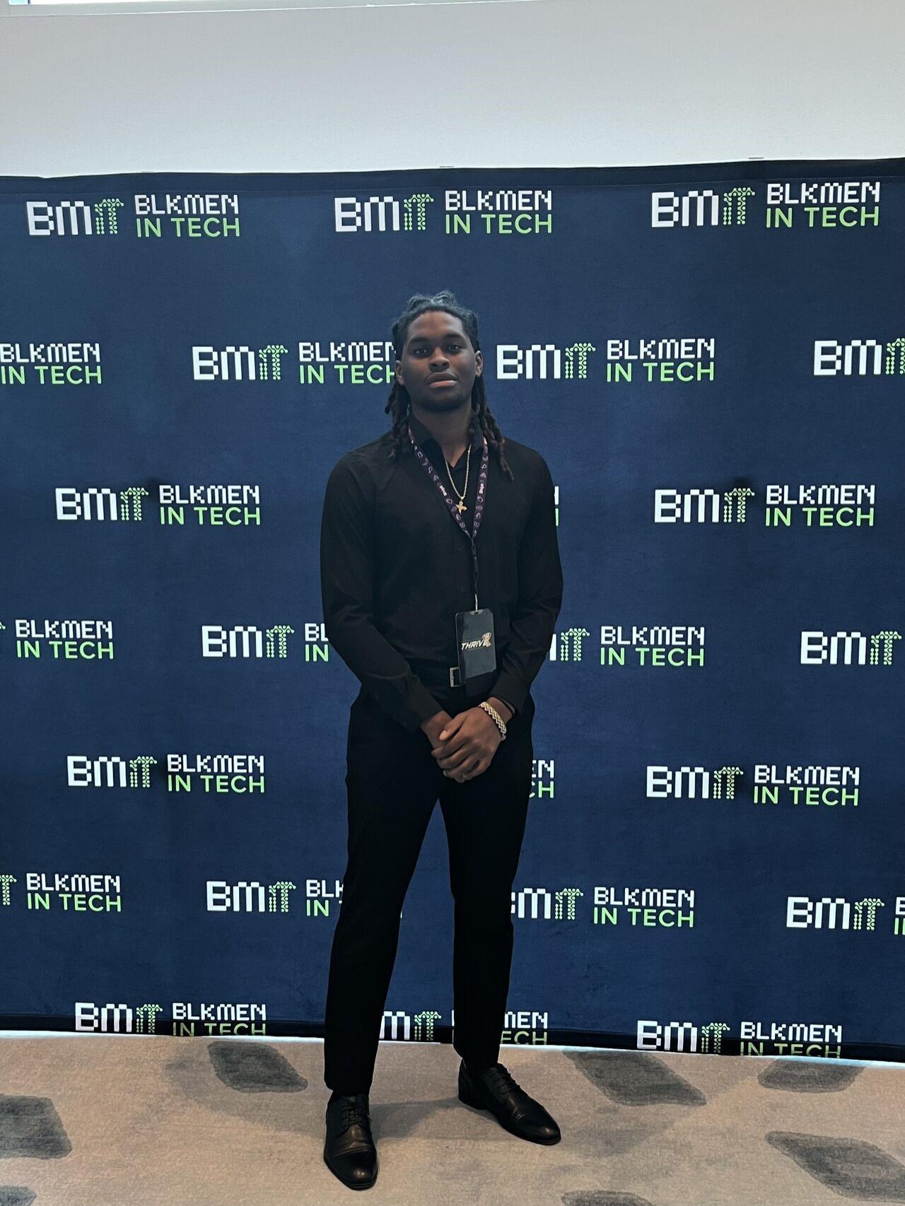 person dressed all in black in front of conference backdrop