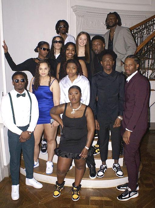 A large group of students wearing dressy clothing and sneakers in front of a staircase.