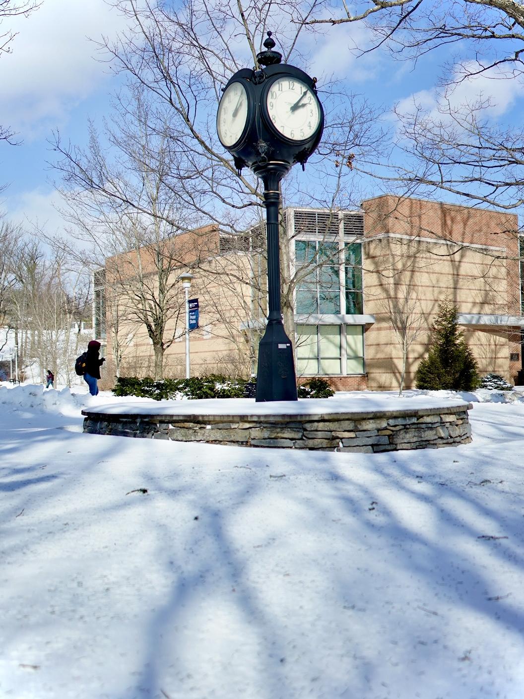 A clock tower on a sunny day with snow on the ground