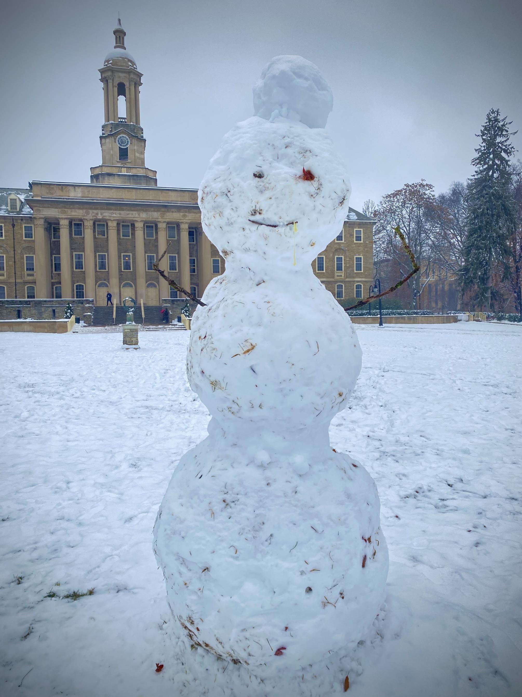 A snowman with Old Main in the background