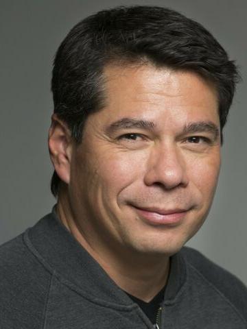 Middle-aged man with dark hair and a clean-shaven face smiling