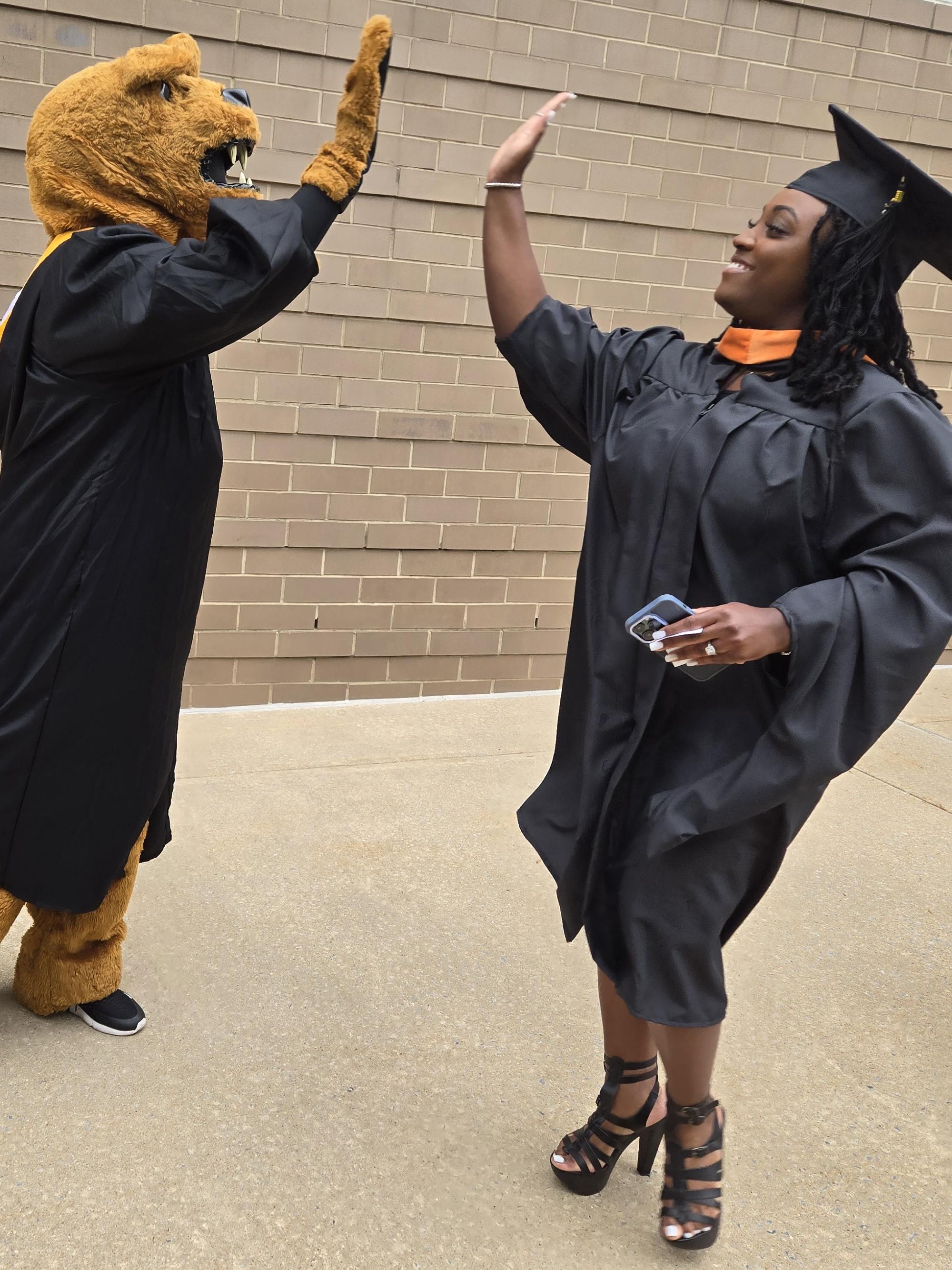 A graduate high-fives the Nittany Lion