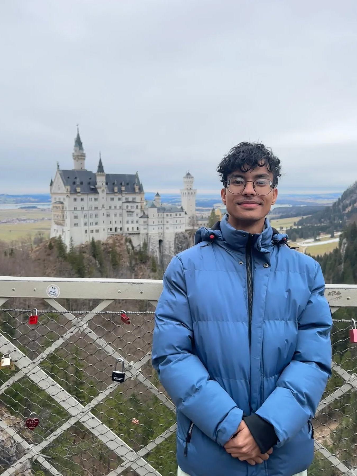 A student poses in front of a far-away castle
