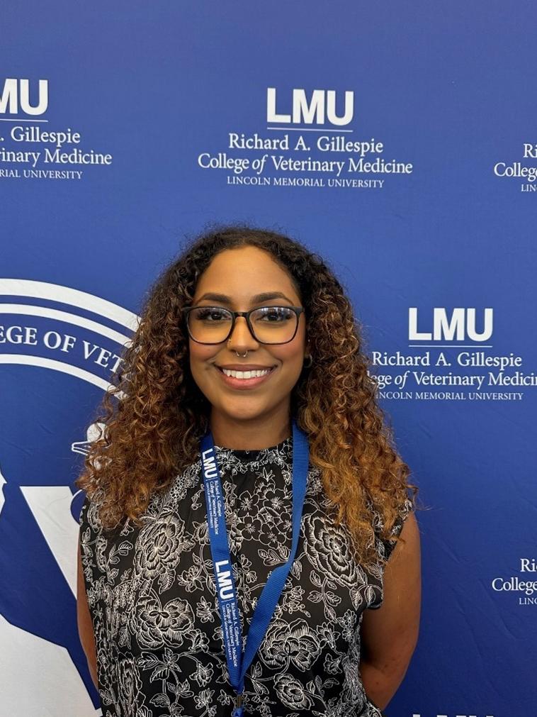 A woman smiling in front of a Lincoln Memorial University media banner