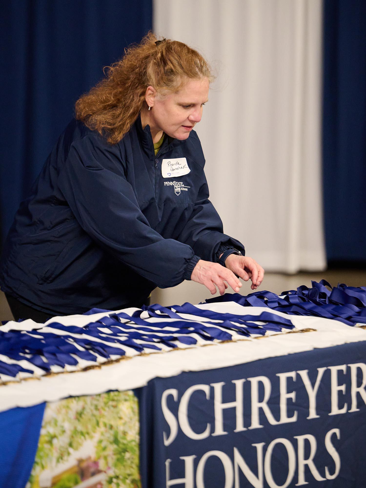 A woman with red hair sorts and straightens medals laid out on a table