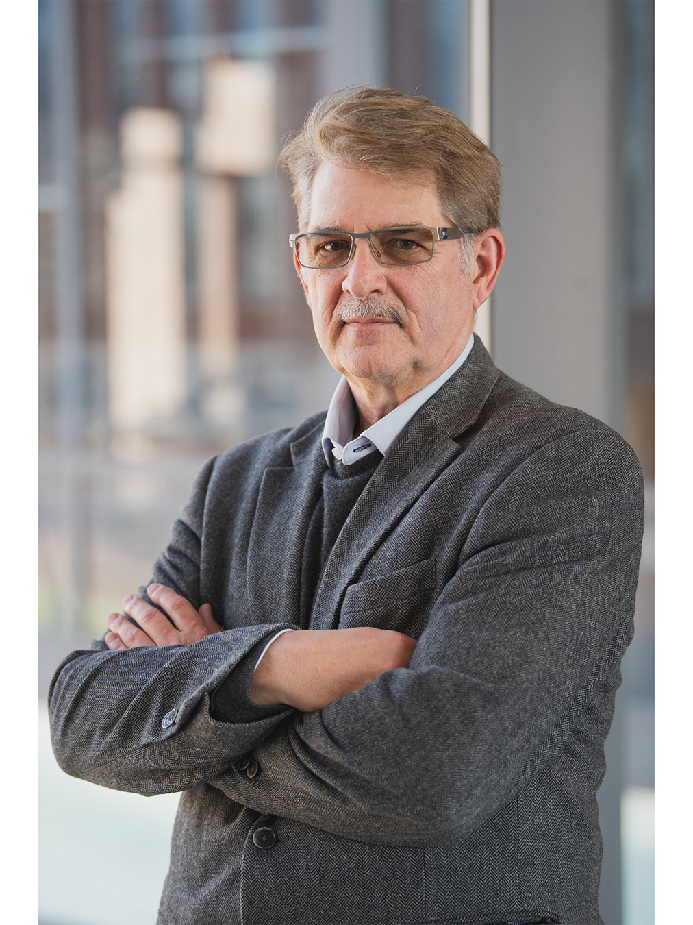 portrait of professor standing with arms crossed across his chest