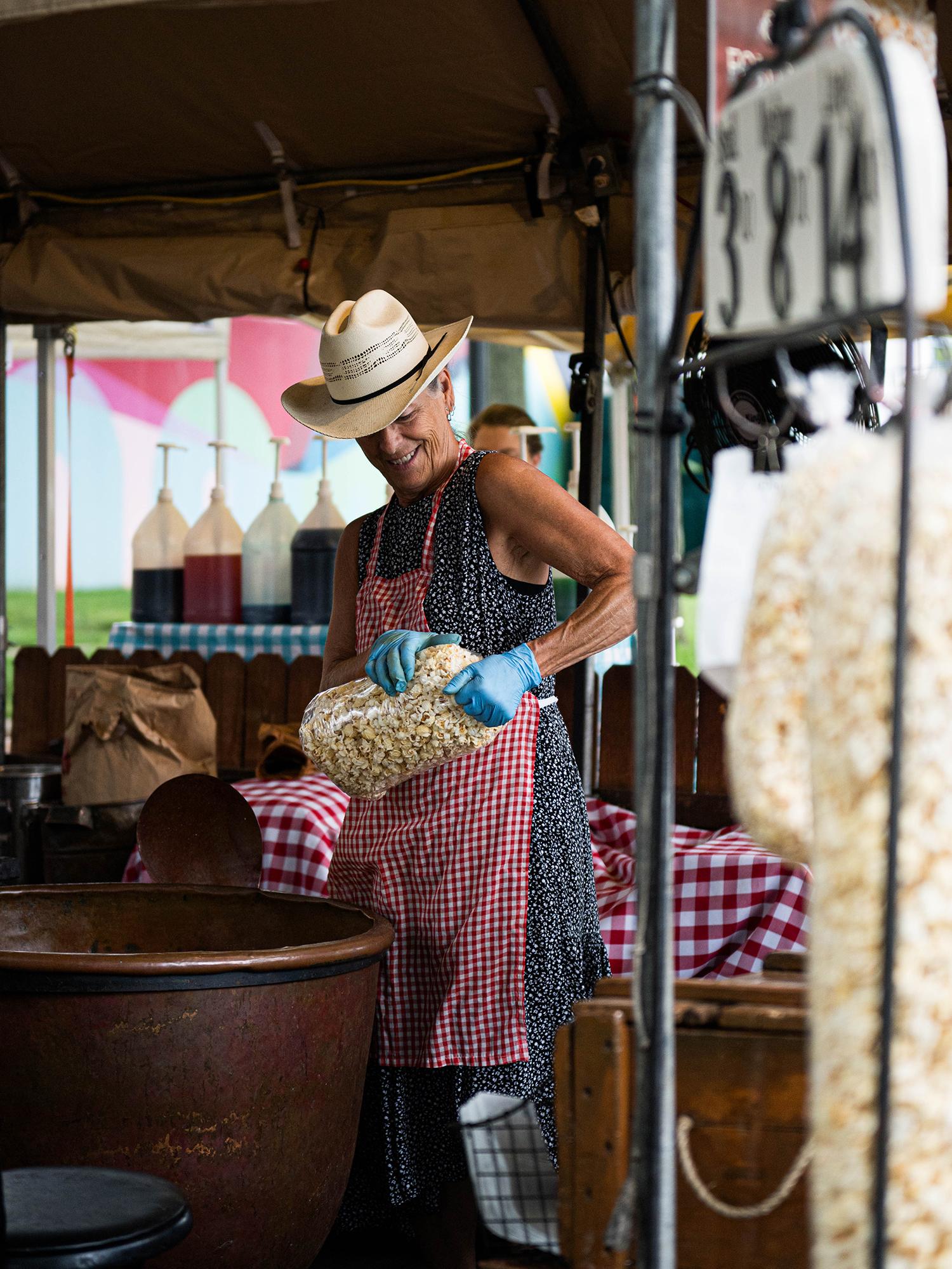 A woman holds a bag of kettle corn inside a tent