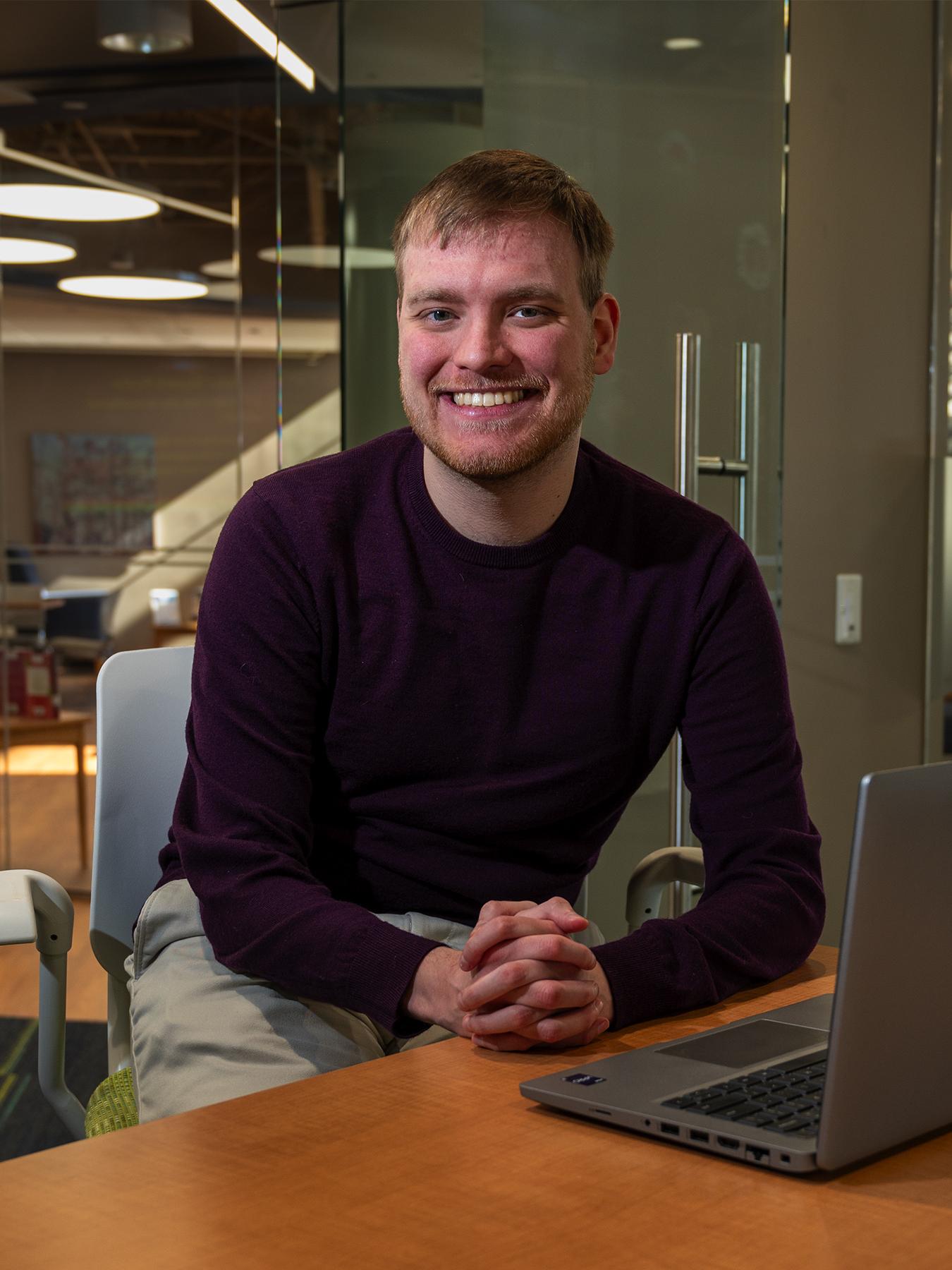 Master of AI student Nicholas Gahman sits at a desk in front of a laptop in Penn State Great Valley's Technology Commons.