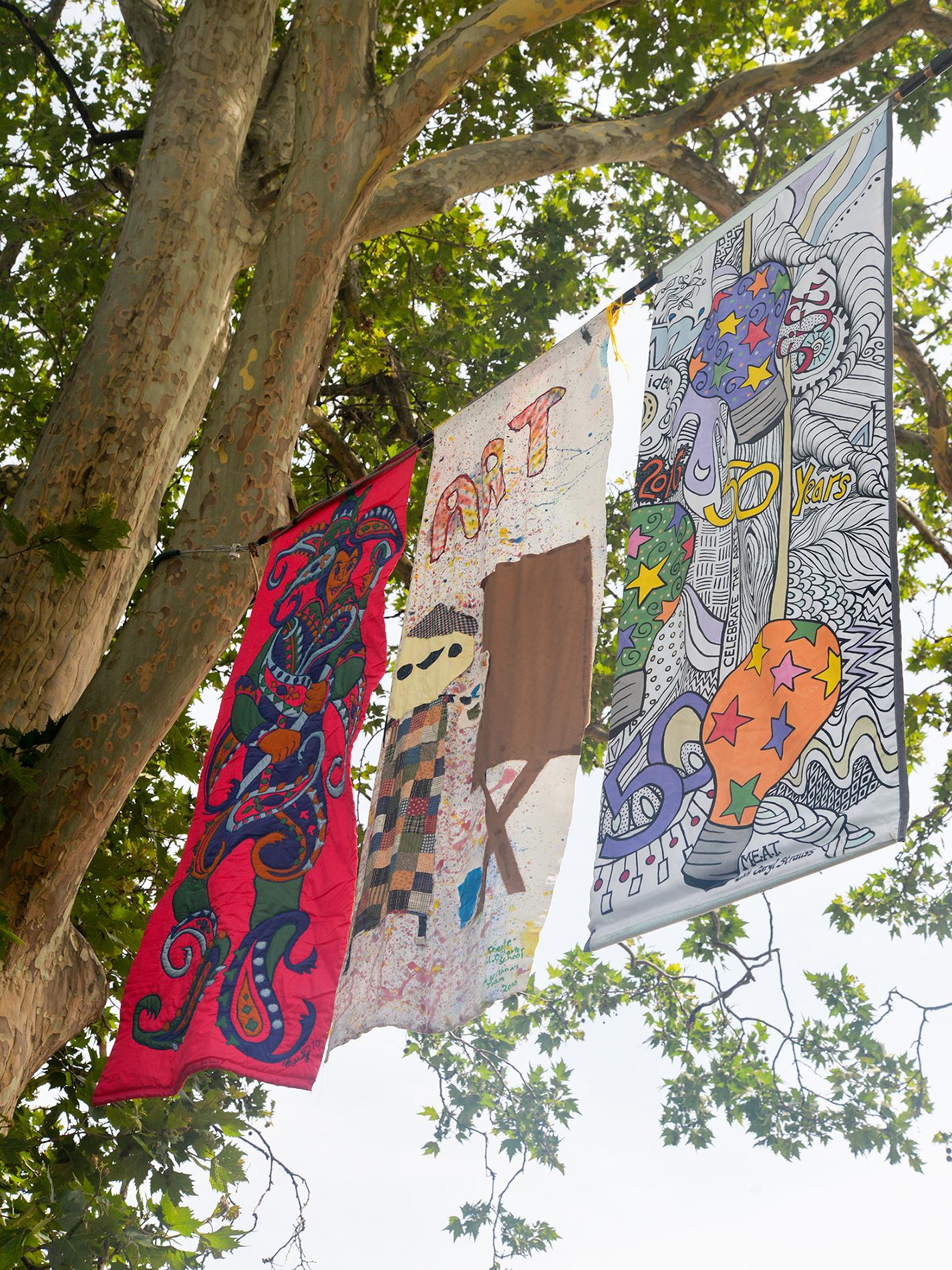 Three colorful banners sway high in the breeze above the street