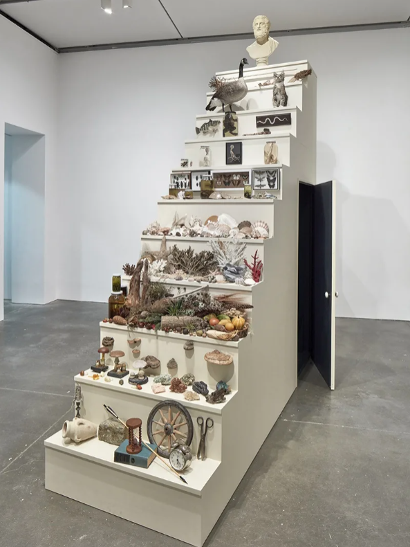 A sculpture of a stairway with objects in graduating hierarchy