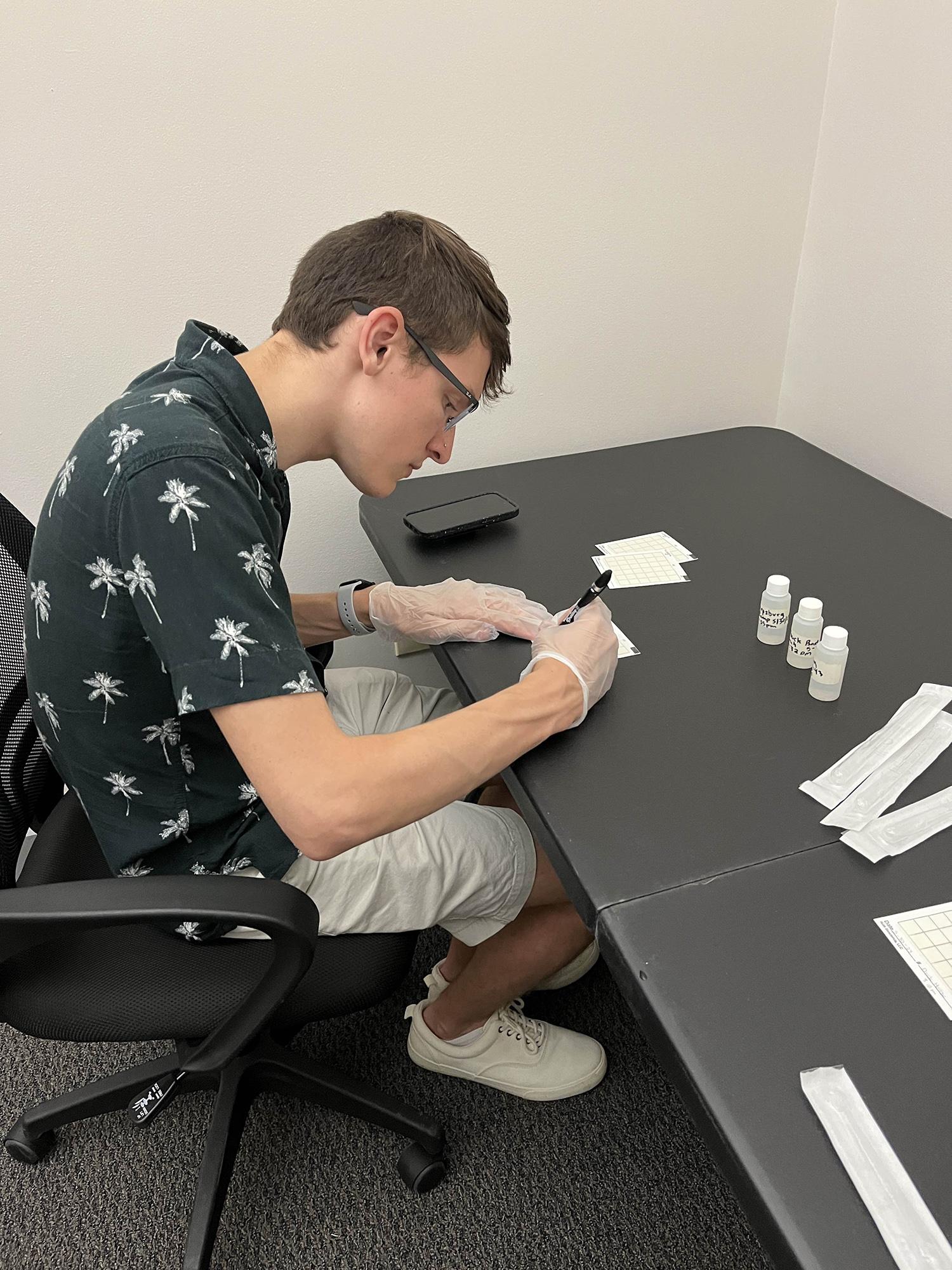 Student performing tests on water samples while sitting at a desk.