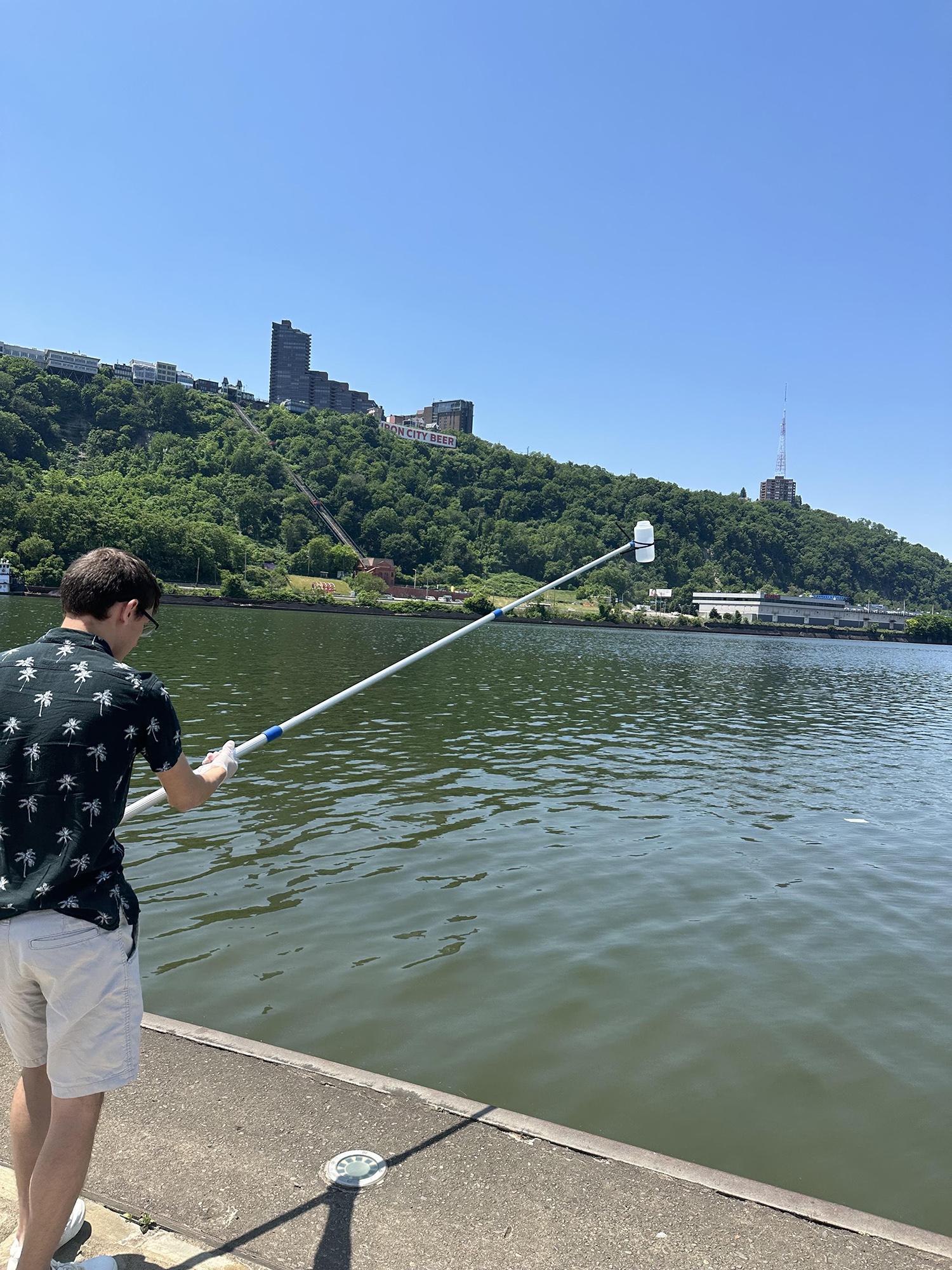 Student retrieving sample of water from the river