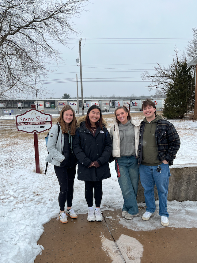 University students pose in front of a sign at a senior center