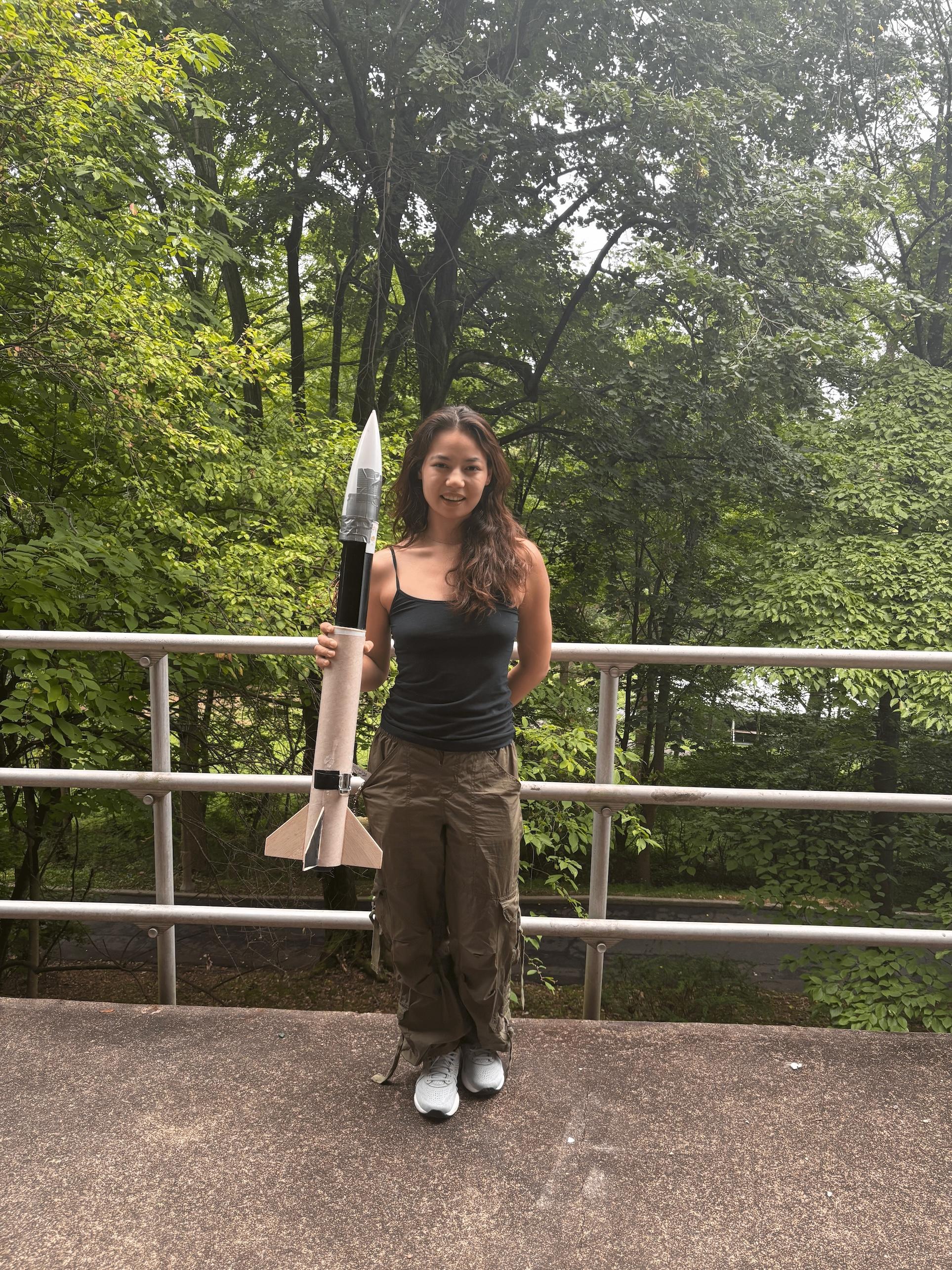 Woman holding a rocket in front of trees