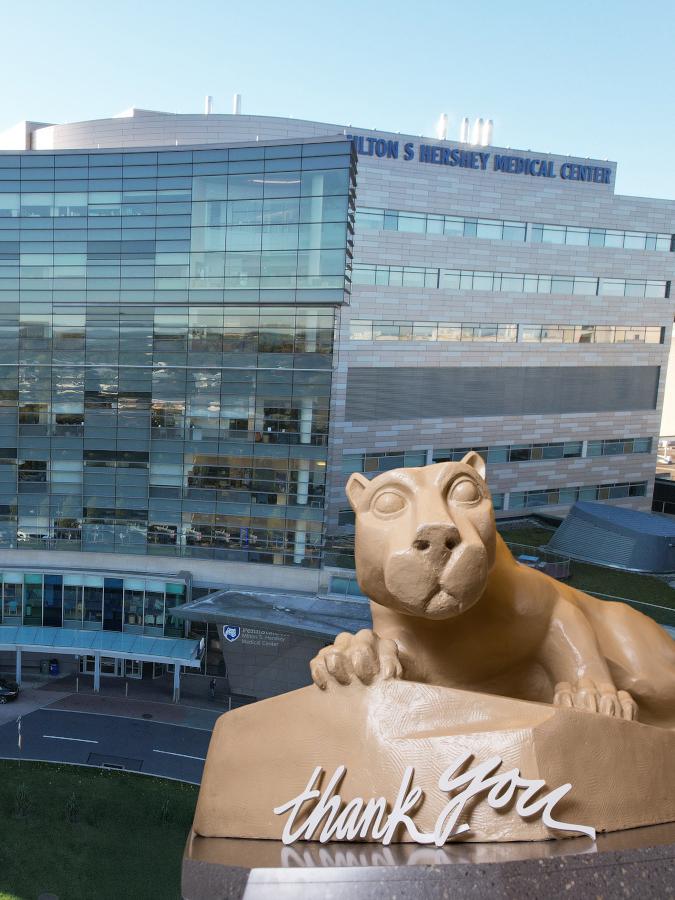 A statue of the Penn State Nittany Lion with the words "thank you" placed in front of it, is superimposed over an exterior image of Penn State Health Children's Hospital.