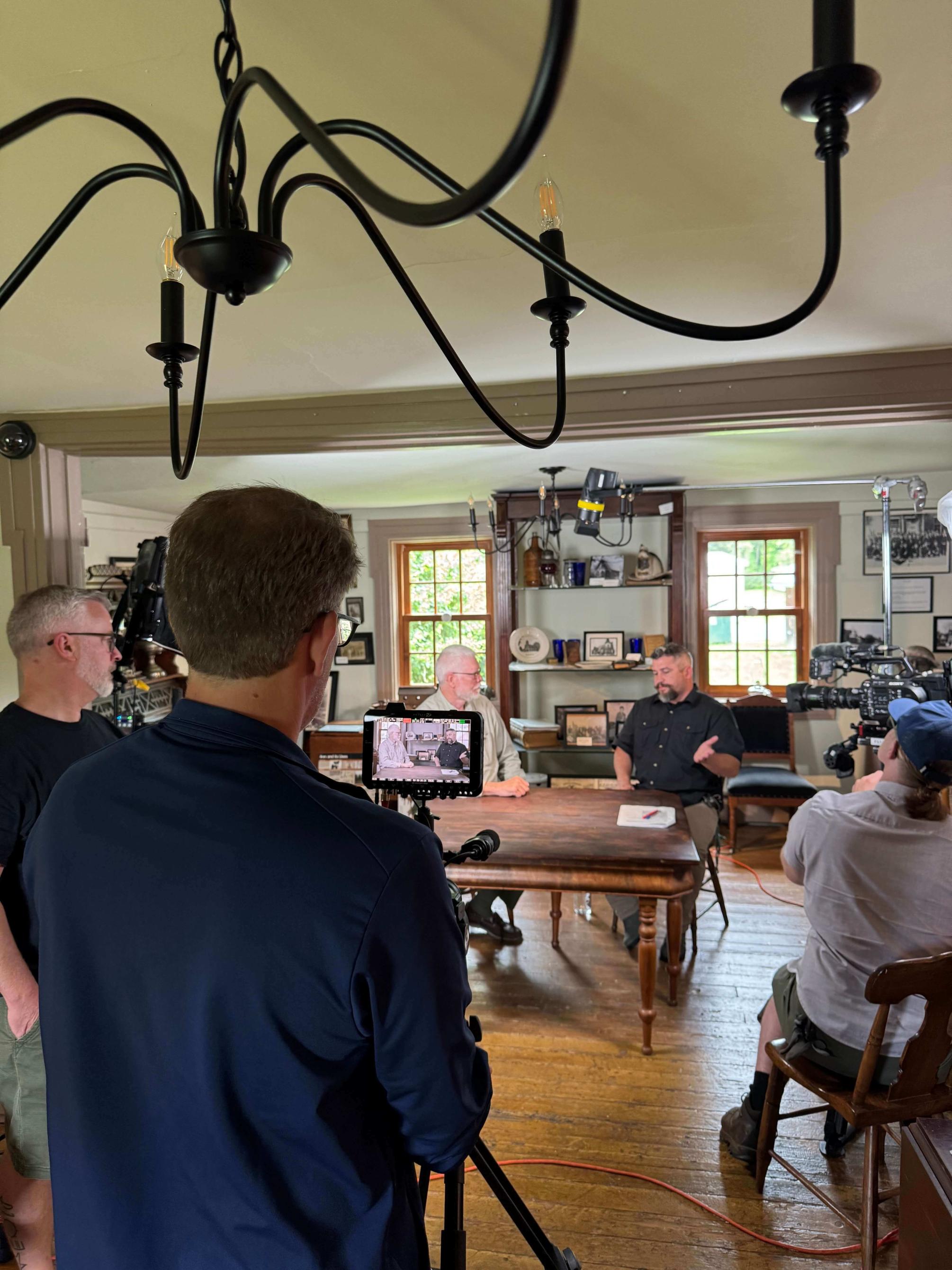Production crew filming people sitting on the set of a television series.