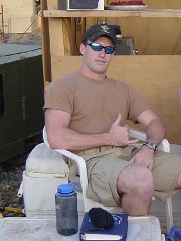 A man wearing tan clothing sits in a chair.