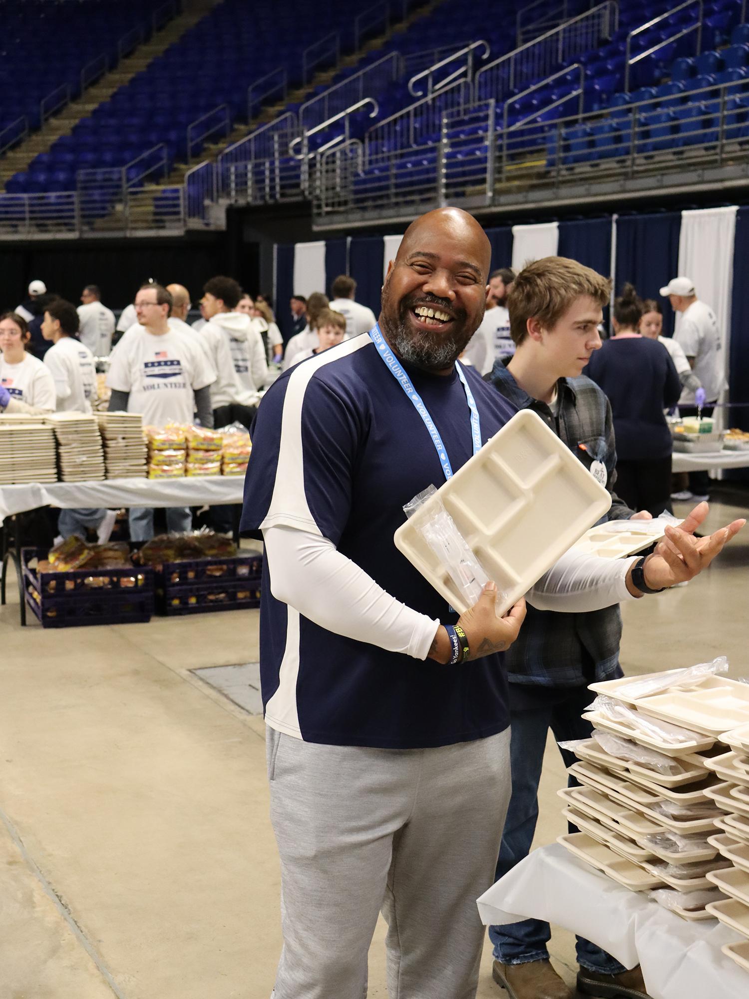 A man holds a food tray in an indoor arena.