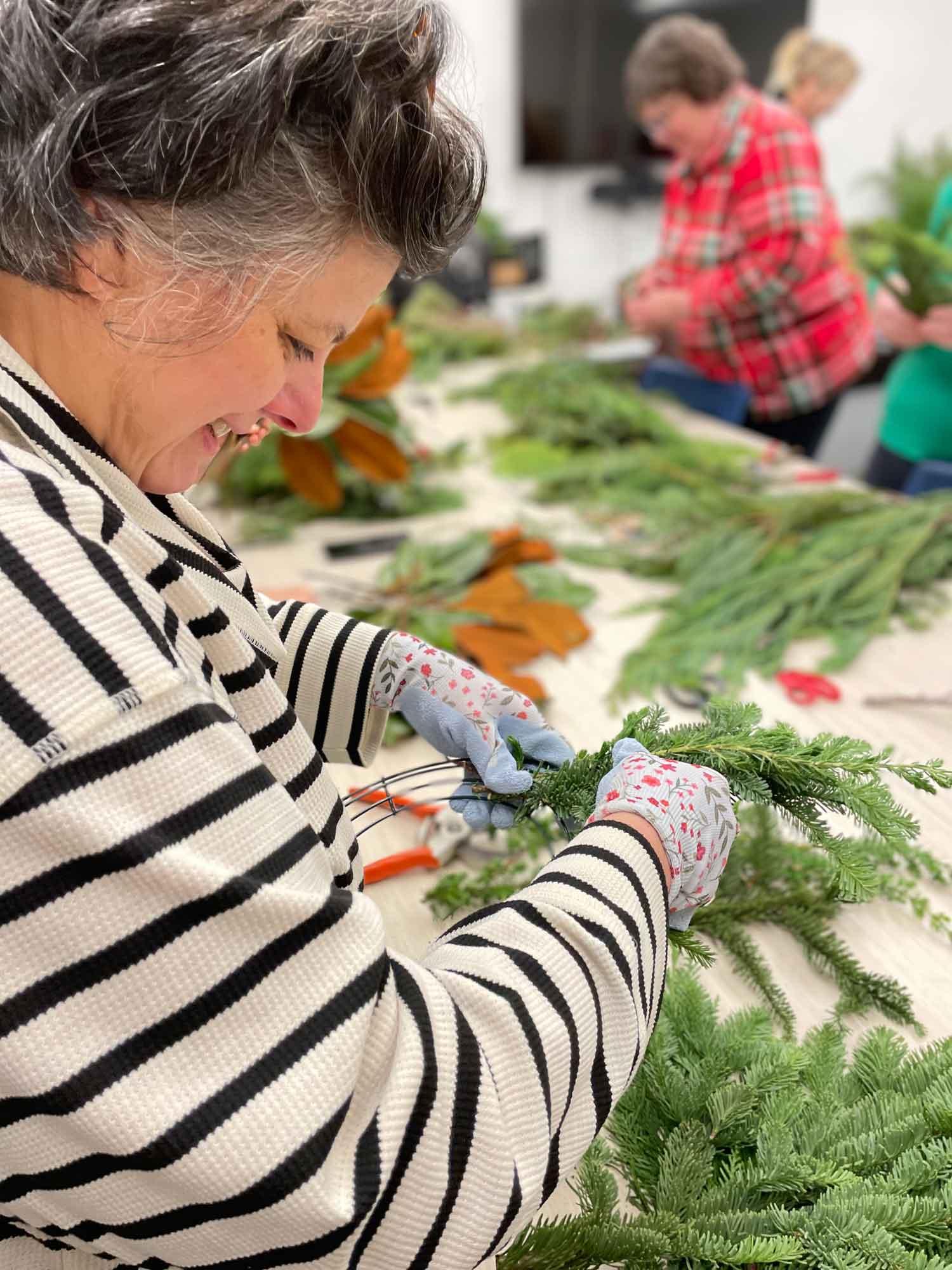 A woman cuts and assembles garlands during a craft class