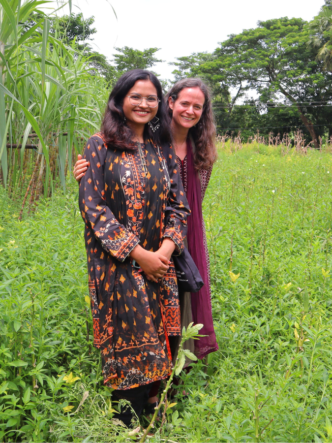Jessica Grembi and Nazifa Tabassum in a grassy field smiling for the camera