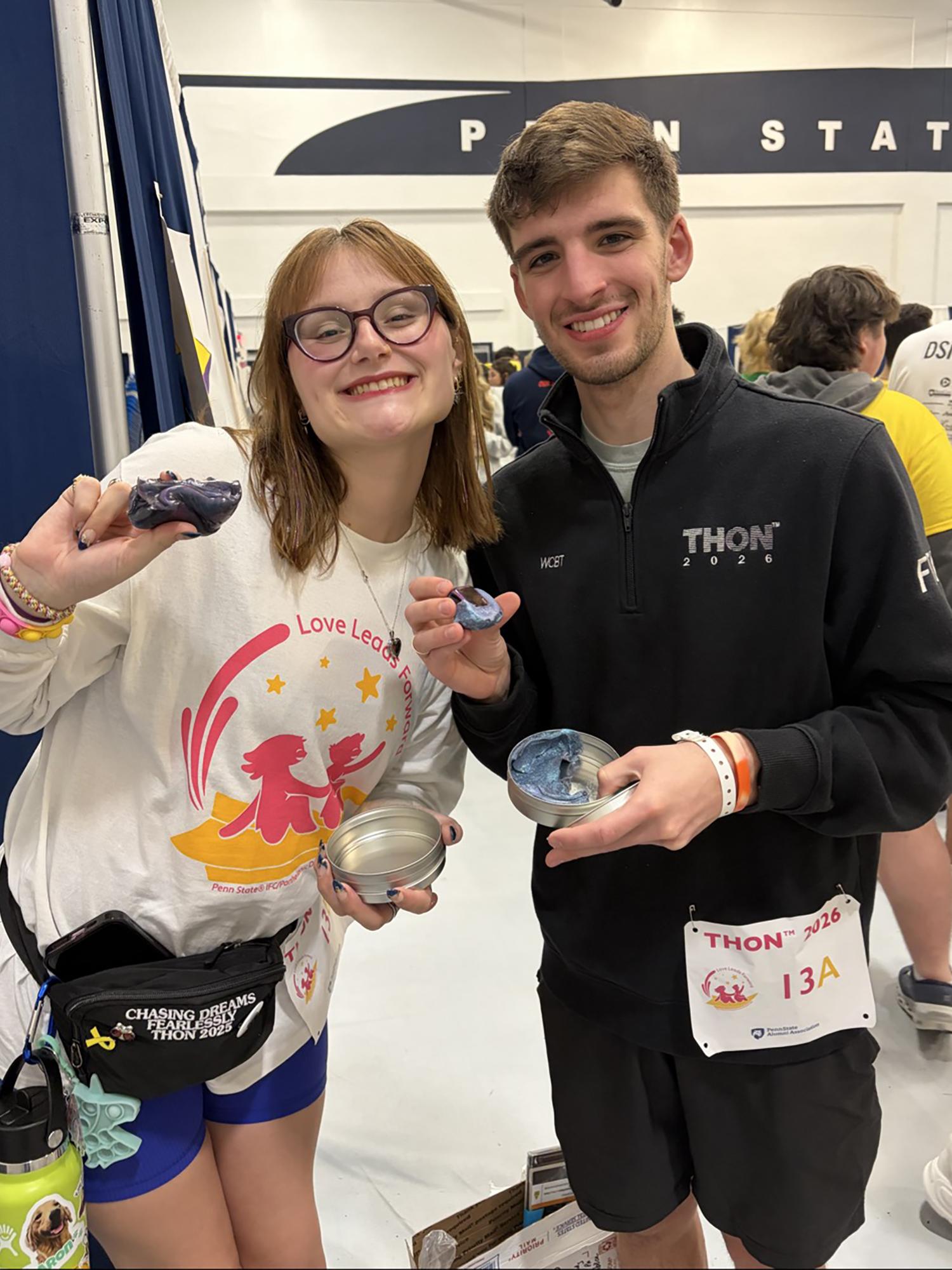 Two people pose in a gym holding clay.