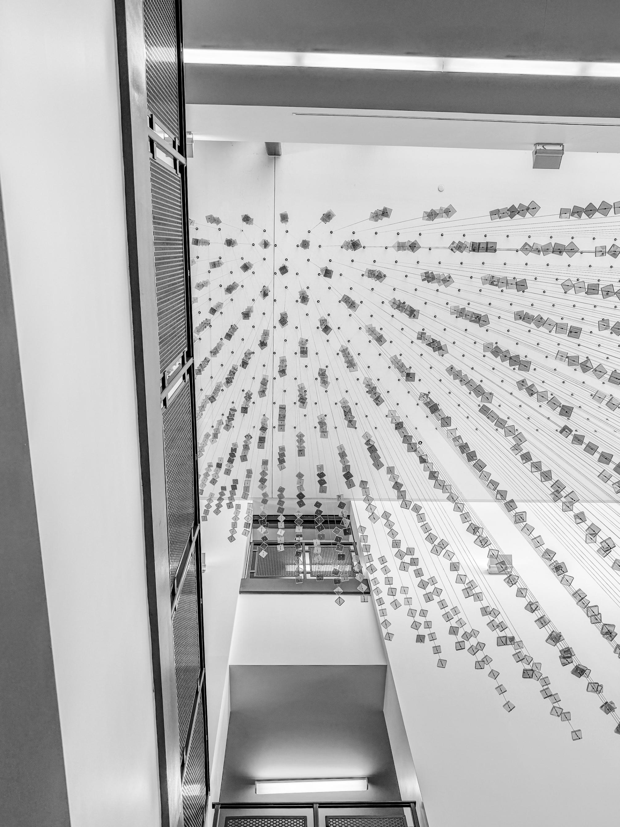 A black-and-white shot from the ground of decor hanging from a ceiling