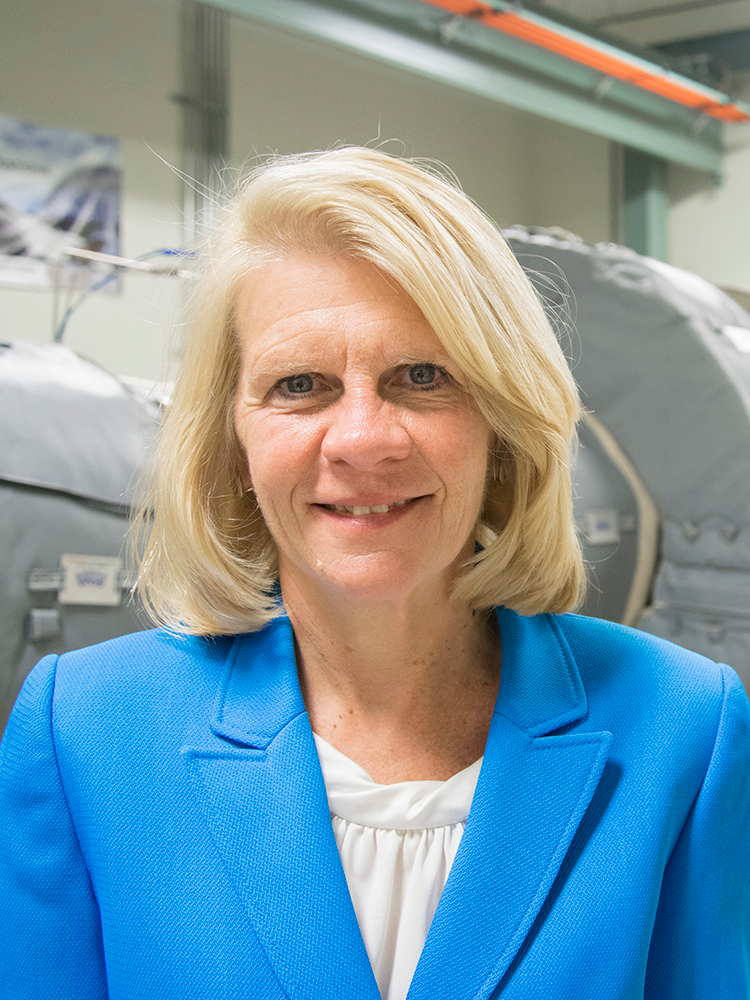 Karen Thole pictured in the Steady Thermal Aero Research Turbine Lab at Penn State, with a gas turbine engine in the background