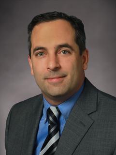 Alan Wagner wears a gray sport coat with blue shirt and striped tie 