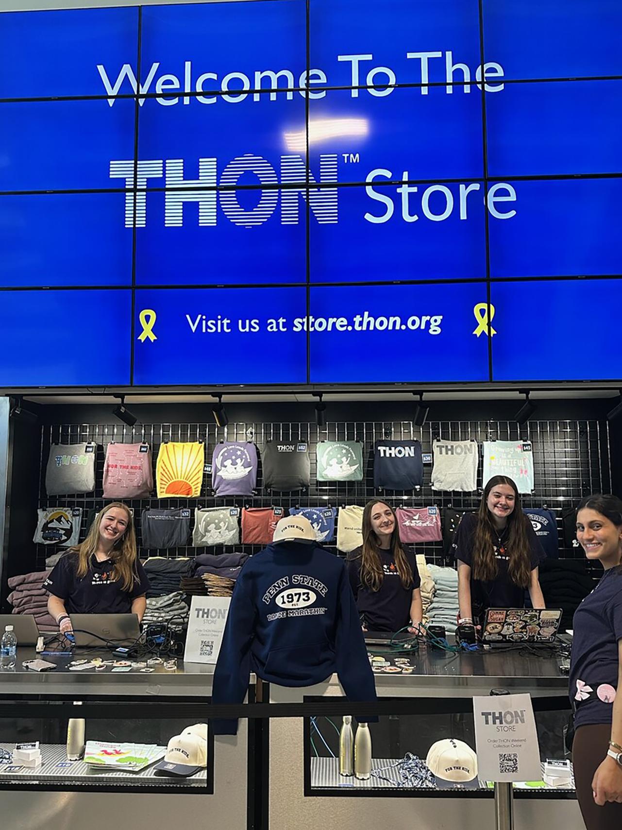 Four female students pose in the store front of the THON Store at the Bryce Jordan Center.