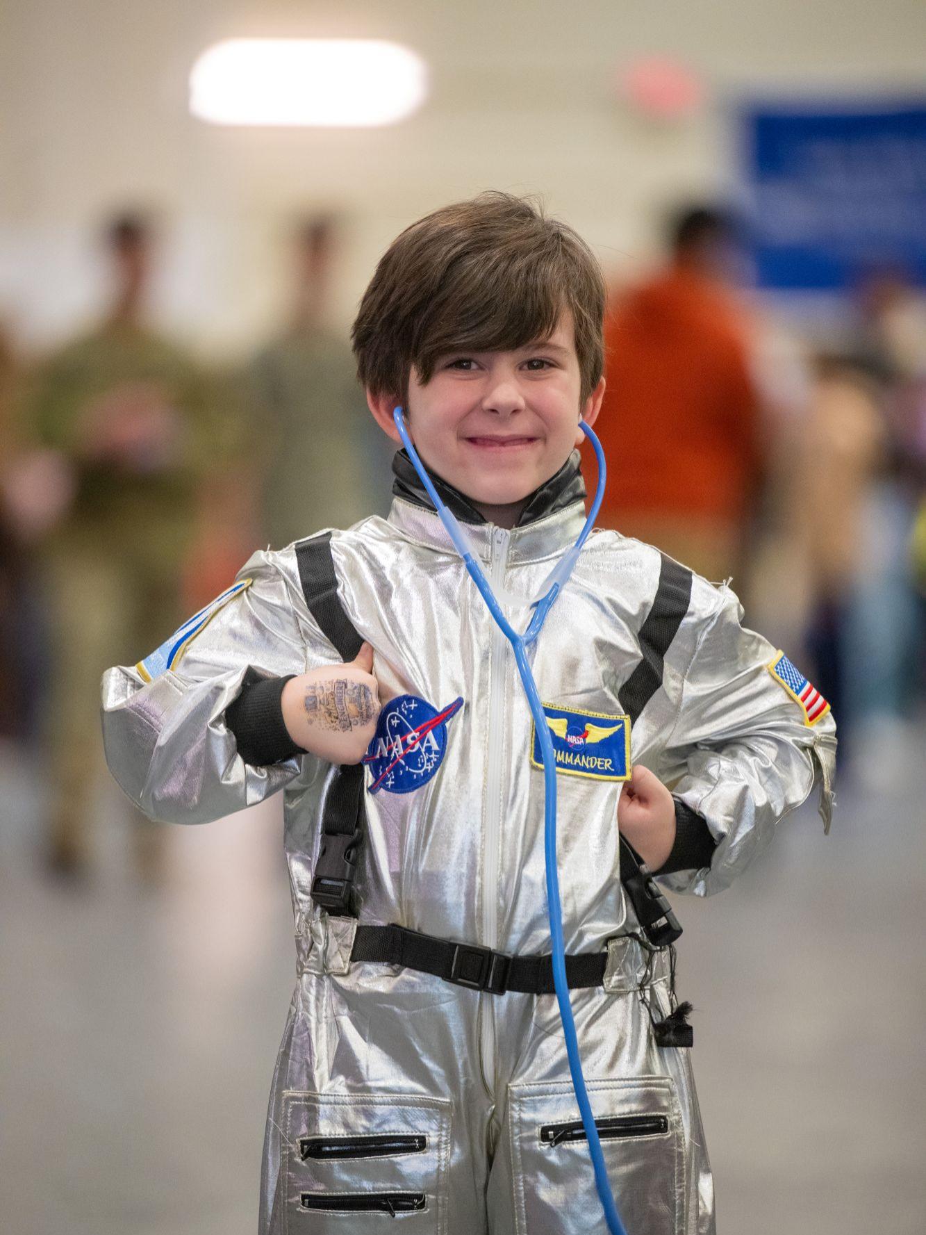 A boy in an astronaut costume smiles while posing at Penn State Behrend's STEAM Fair.
