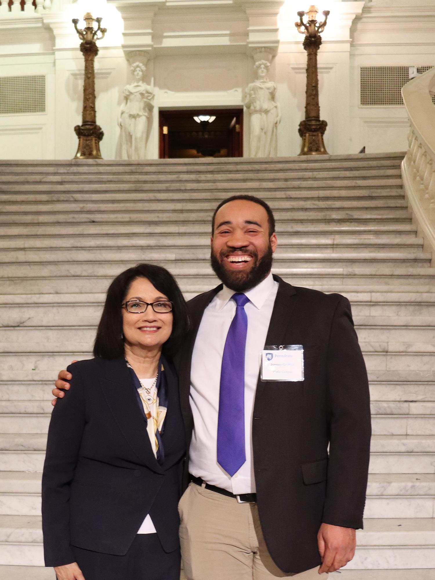A man and woman stand in front of a large set of marble stairs.