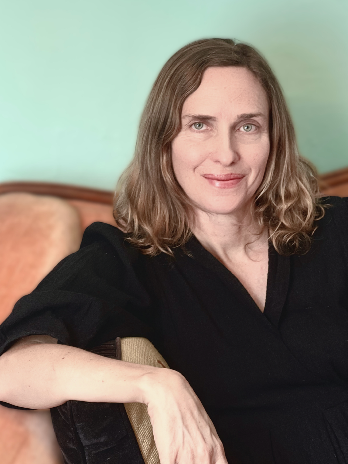 A photo of Deborah Lutz reclining on a sofa and smiling