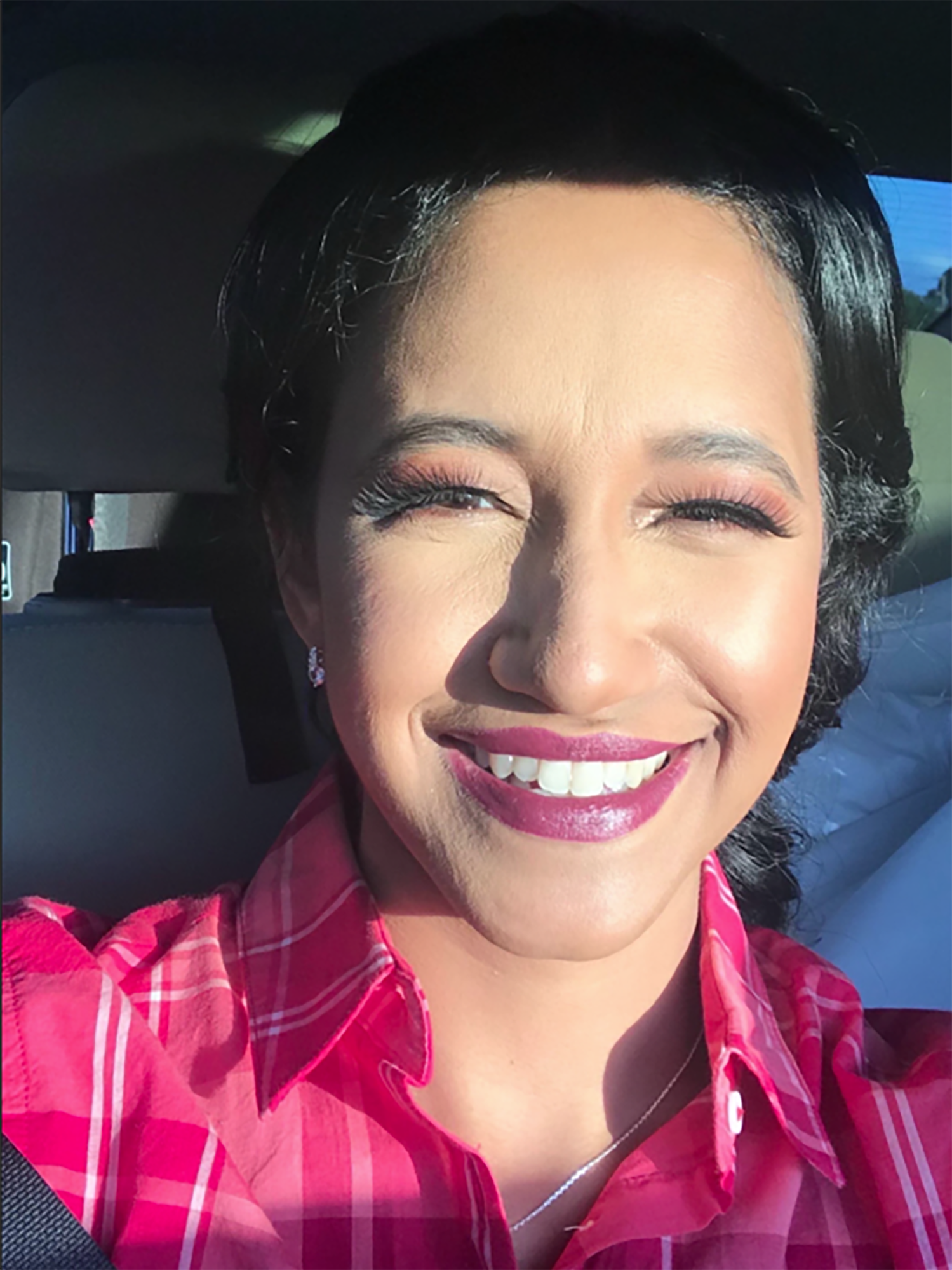 A woman wearing a pink shirt in a car.