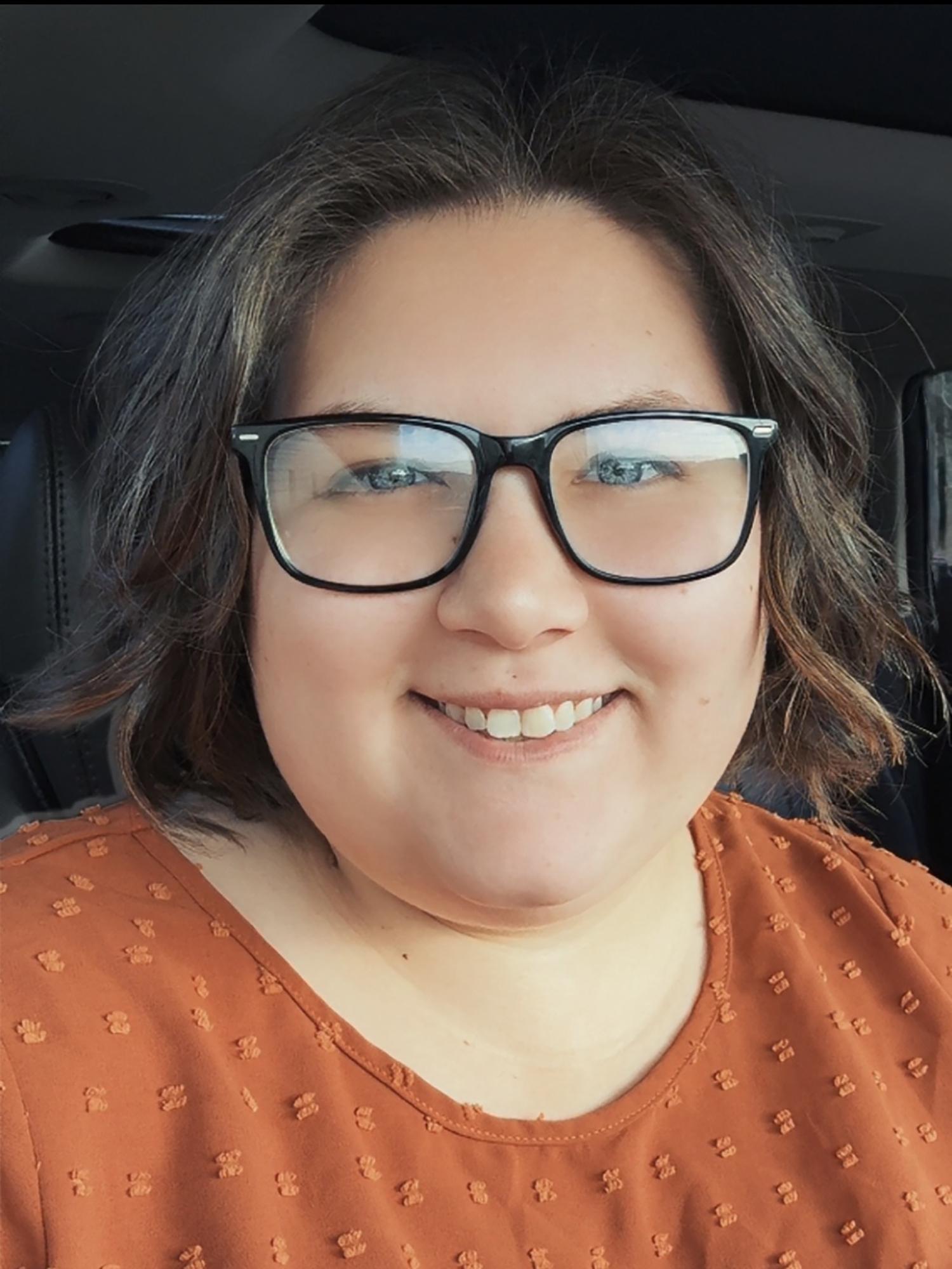 A woman wearing glasses and an orange shirt.