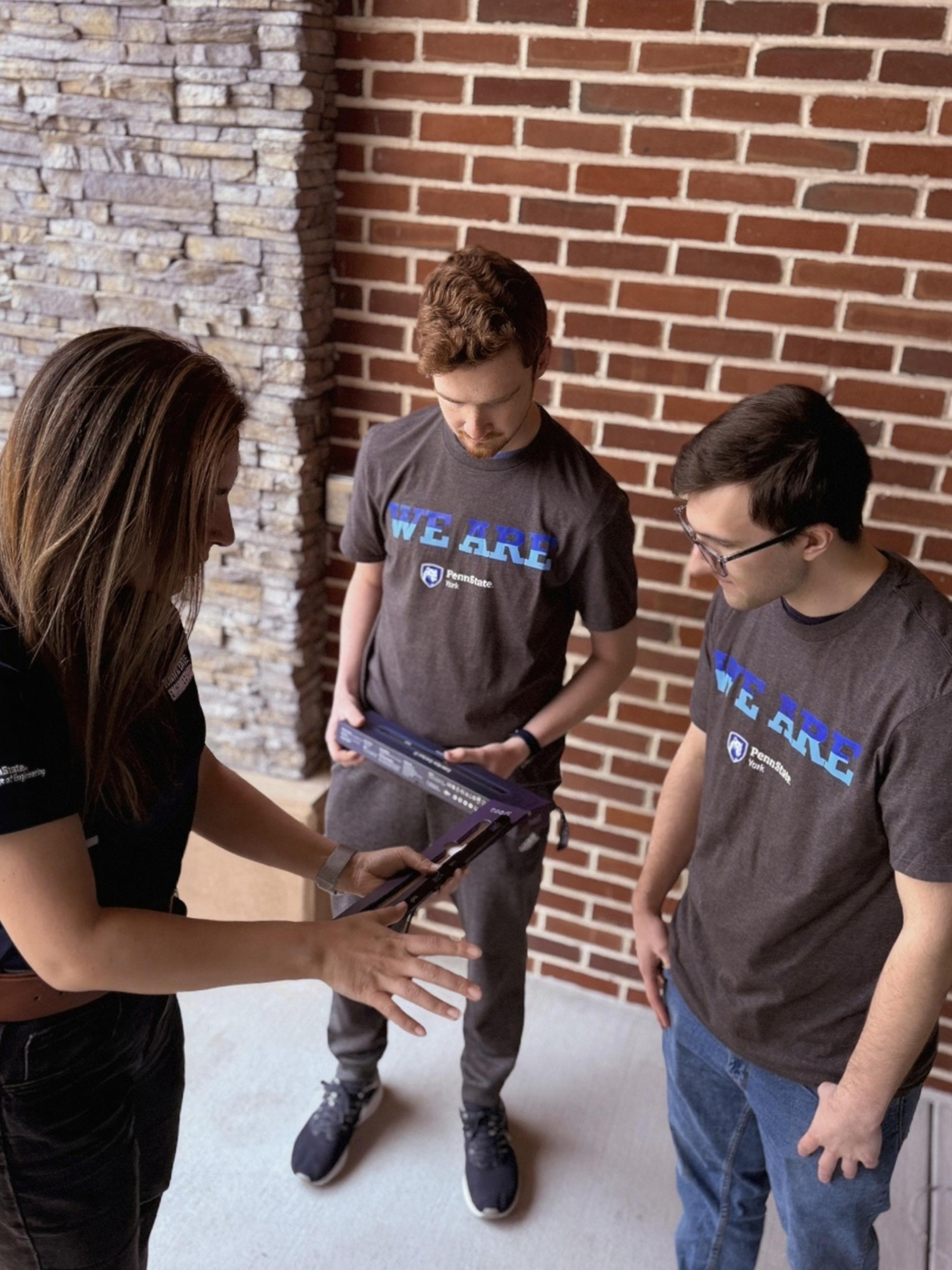 Two students stand with their professor