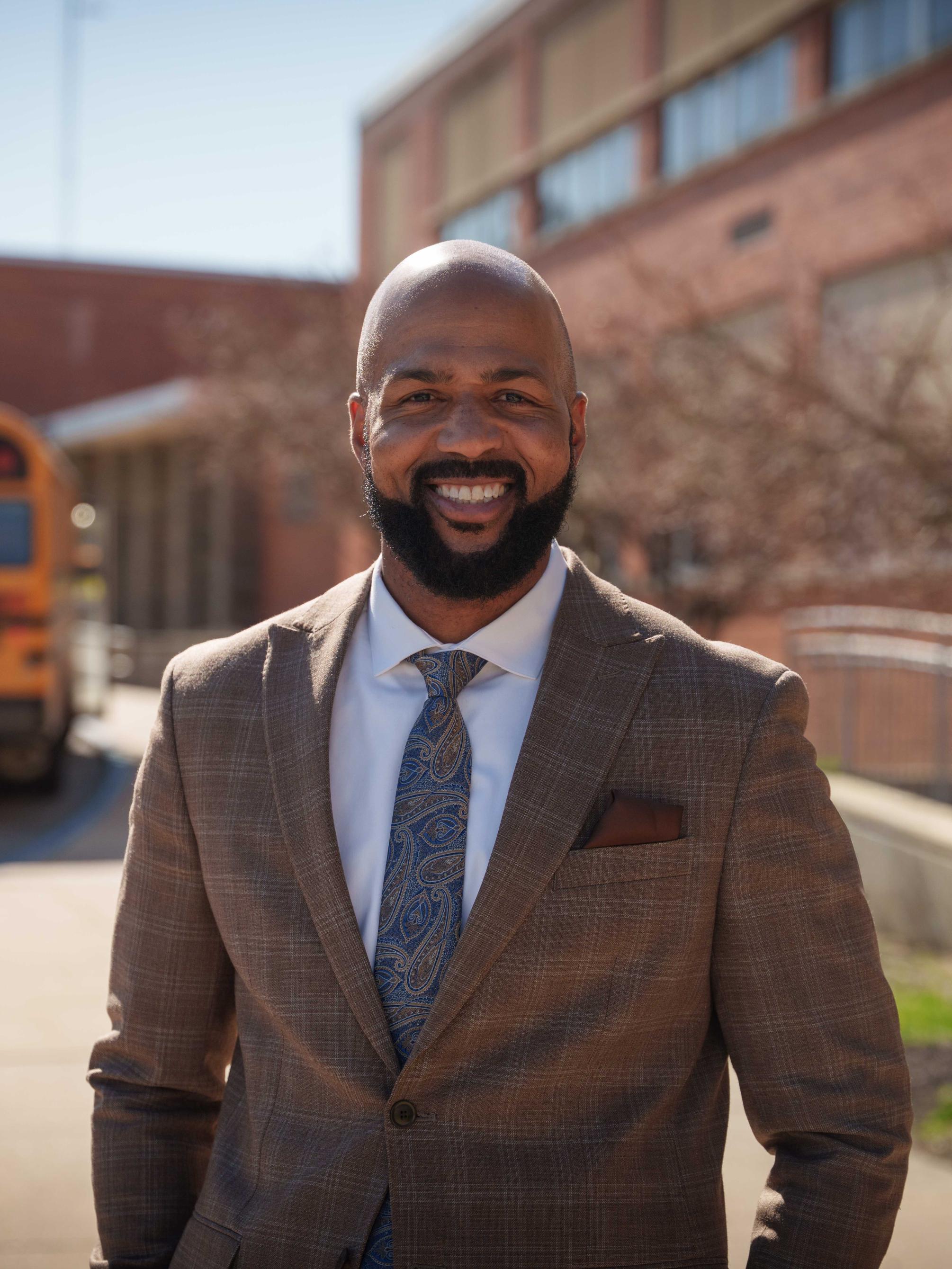A man wearing a suit and tie standing in front of a school