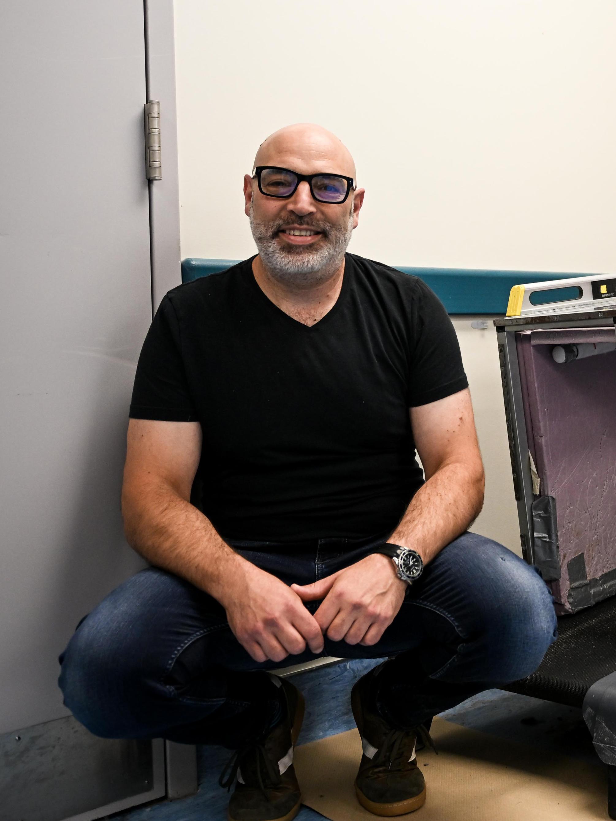 Jonas Rubenson crouches beside a treadmill. On the treadmill is the metabolic chamber, a Lucite box with tubes for airflow.