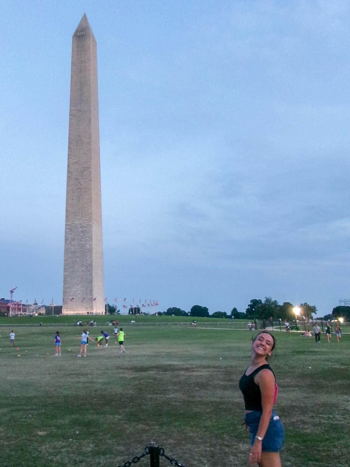 Ashlyn Gilchriest poses outdoors at dusk with the Washington Monument in the background.