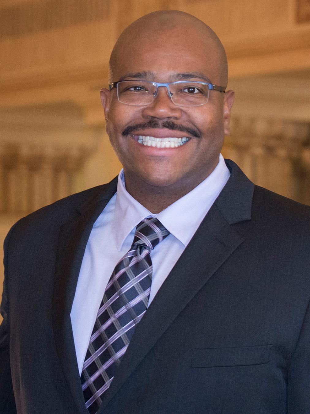 A smiling Lance Kennedy-Phillips wearing a business suit and tie