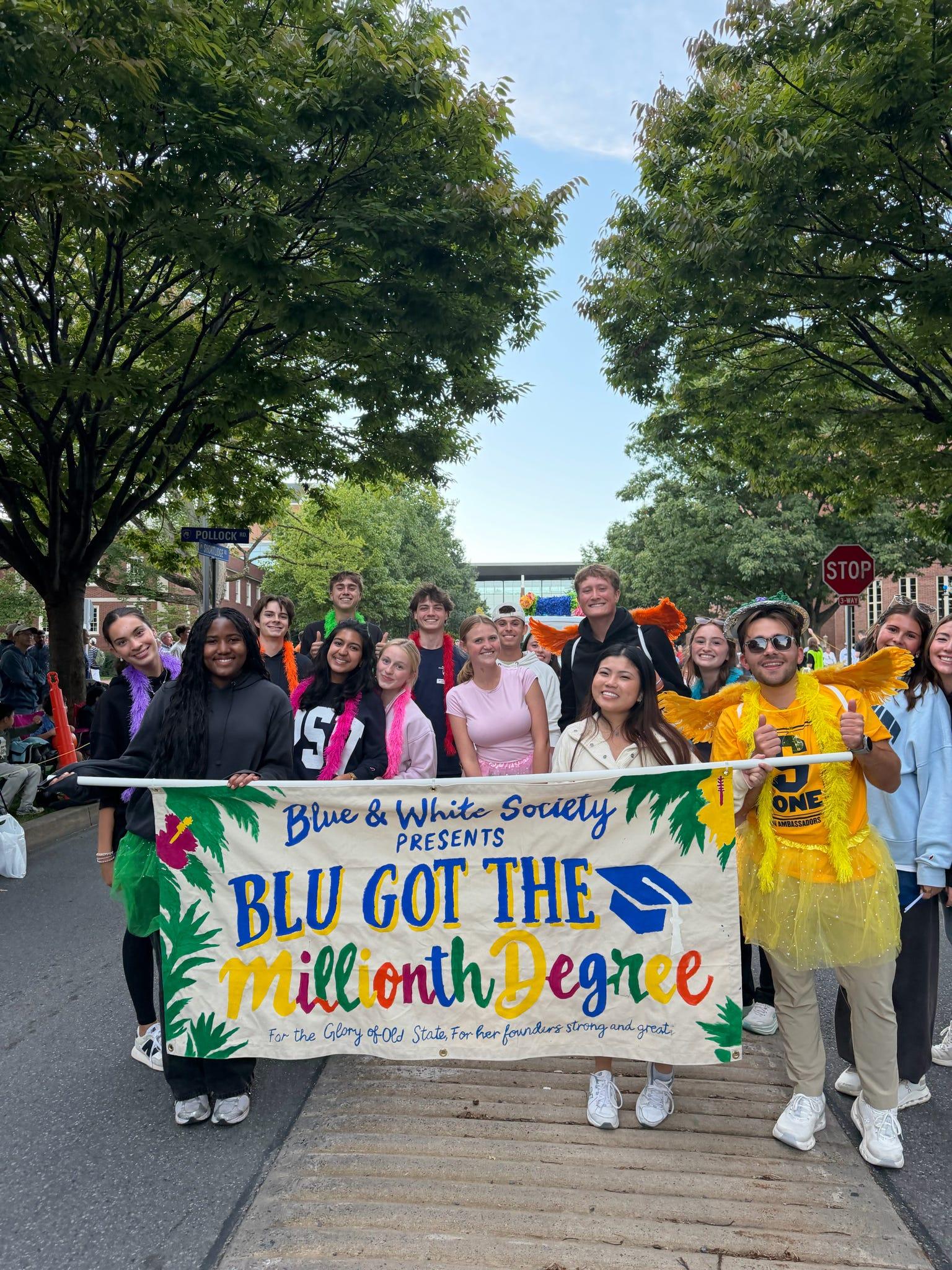 A group of students hold a banner that reads "Blu got the millionth degree"