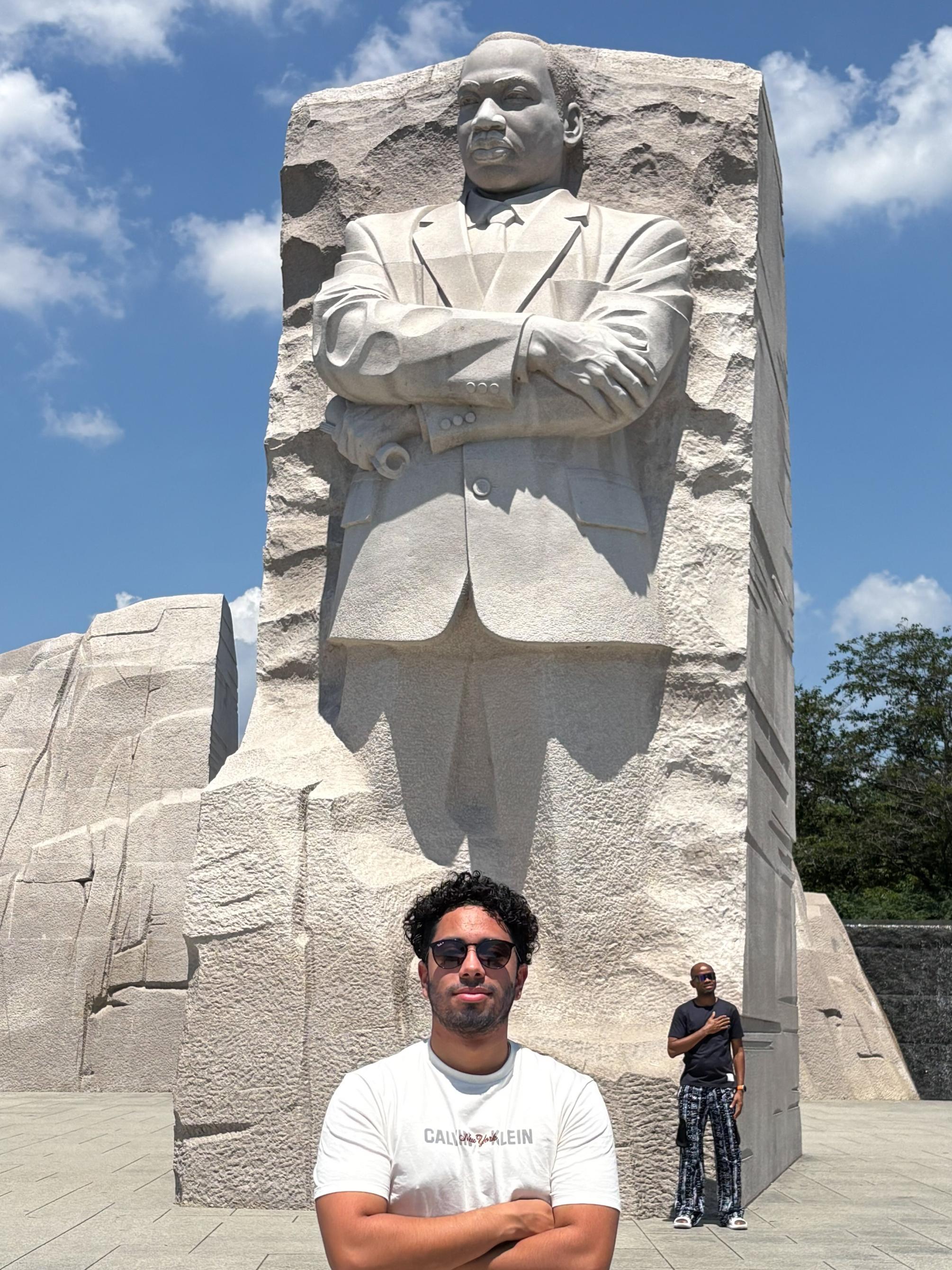 Daniel Garcia Calao wears a white outfit while standing in front of a carved statue of Martin Luther King Jr. at the MLK Memorial in Washington, D.C.