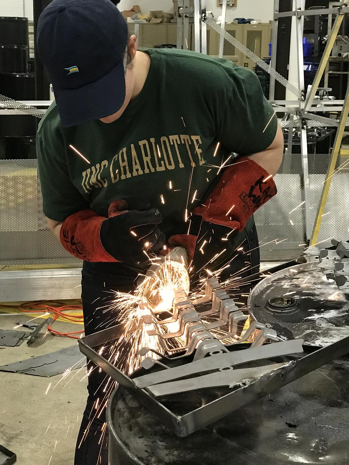 Kacie Ward welds together some of the auto scrap while sparks fly out.