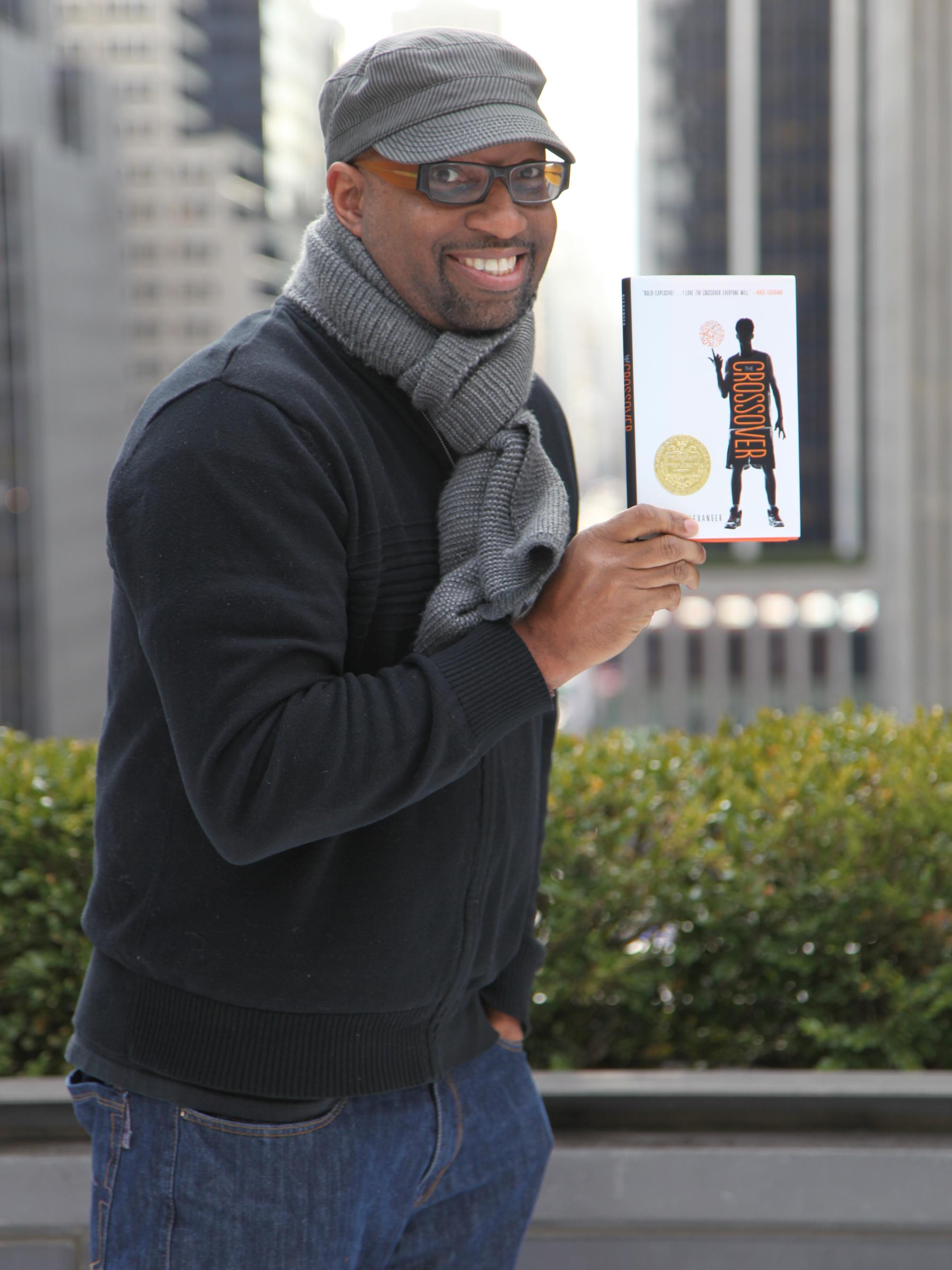 Author Kwame Alexander holding a copy of "The Crossover"